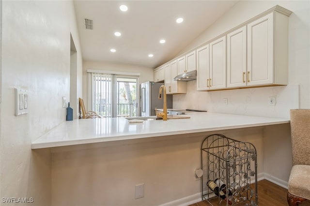 kitchen with stainless steel fridge, kitchen peninsula, vaulted ceiling, and dark wood-type flooring