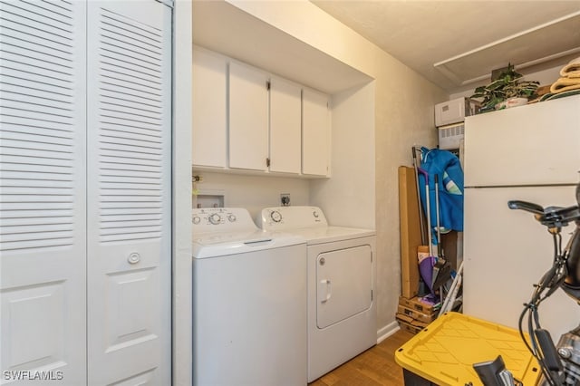 laundry area with cabinets, washing machine and clothes dryer, and hardwood / wood-style flooring