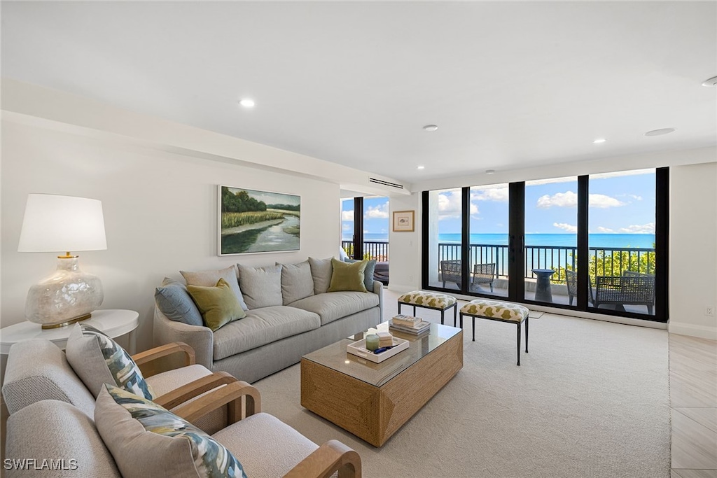 living room with a water view, expansive windows, and light colored carpet