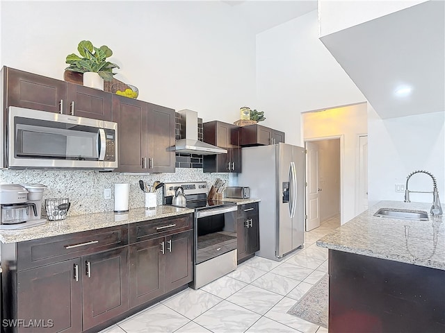 kitchen with sink, dark brown cabinets, wall chimney exhaust hood, backsplash, and appliances with stainless steel finishes