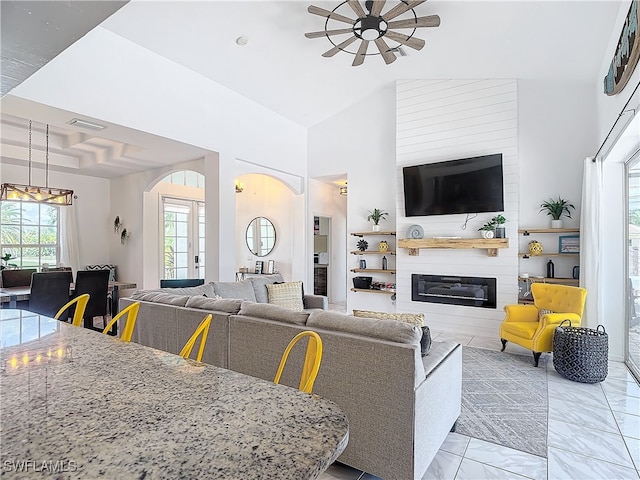 living room featuring ceiling fan, a fireplace, and high vaulted ceiling