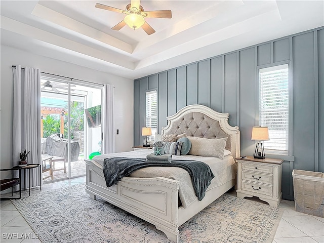 bedroom featuring ceiling fan, a raised ceiling, multiple windows, and access to outside