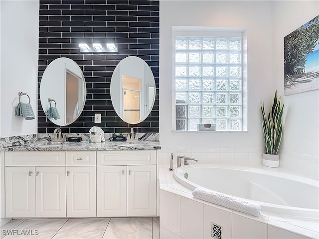 bathroom featuring tiled bath, vanity, and a wealth of natural light