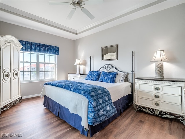 bedroom featuring ceiling fan, dark hardwood / wood-style flooring, and a tray ceiling