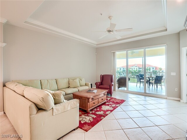 living room with a tray ceiling, light tile patterned floors, and ceiling fan