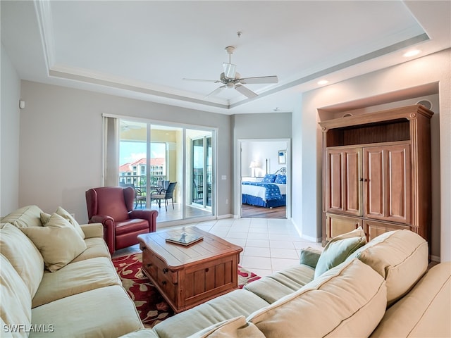 living room featuring ceiling fan, a tray ceiling, and light tile patterned flooring