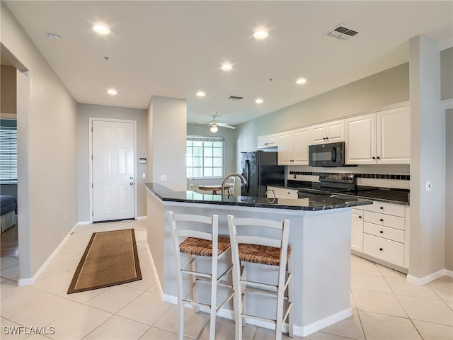 kitchen with a kitchen island with sink, white cabinetry, black appliances, and tasteful backsplash