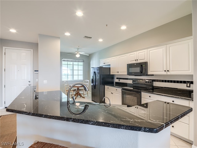 kitchen with white cabinets, dark stone countertops, a large island with sink, and black appliances