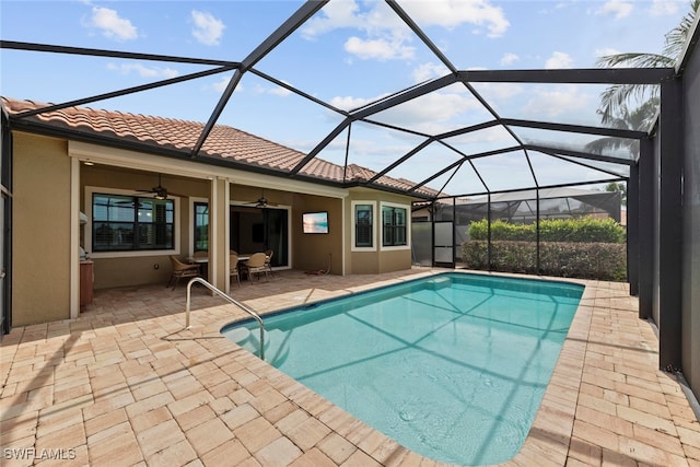 view of pool with a patio area, ceiling fan, and glass enclosure