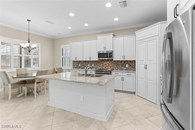 kitchen with light stone counters, an island with sink, appliances with stainless steel finishes, white cabinetry, and sink