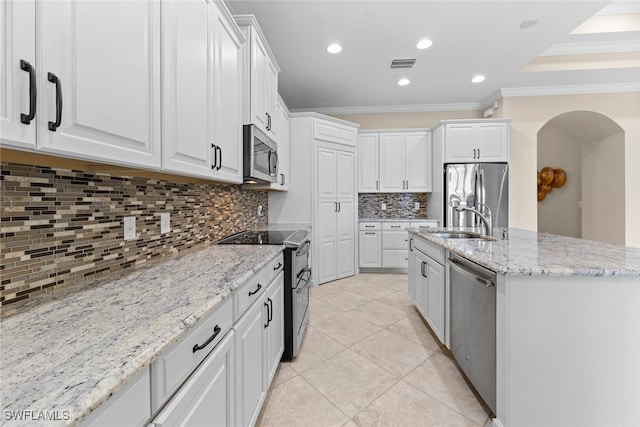 kitchen featuring tasteful backsplash, crown molding, white cabinetry, stainless steel appliances, and light stone counters