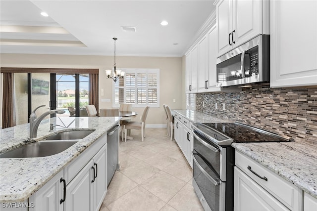 kitchen featuring tasteful backsplash, sink, white cabinetry, stainless steel appliances, and decorative light fixtures