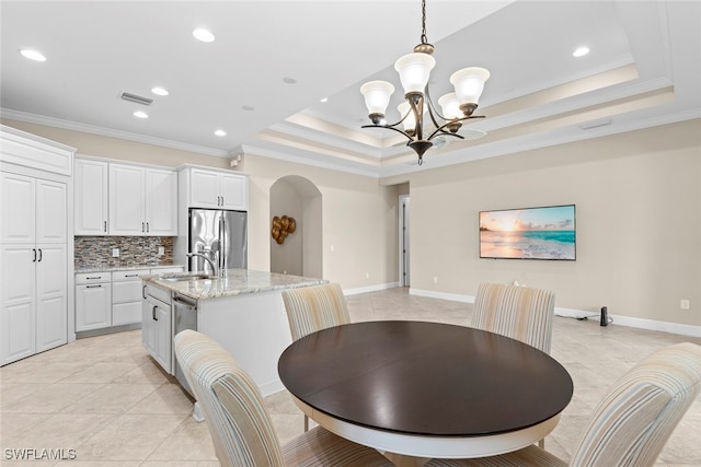 dining space with ornamental molding, sink, an inviting chandelier, light tile patterned floors, and a raised ceiling