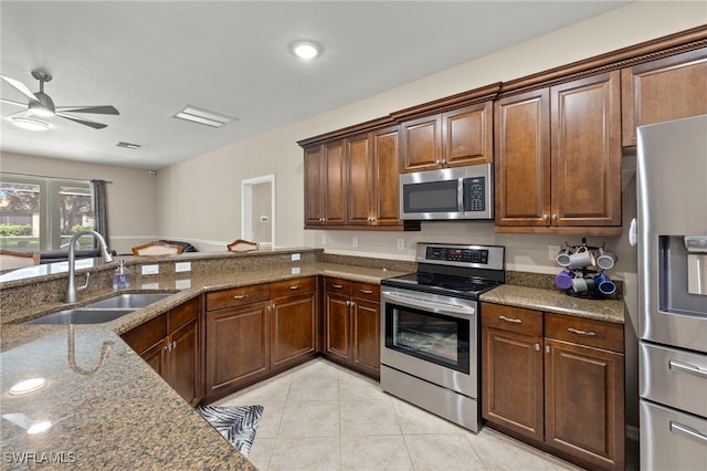 kitchen with stone counters, appliances with stainless steel finishes, sink, ceiling fan, and light tile patterned floors