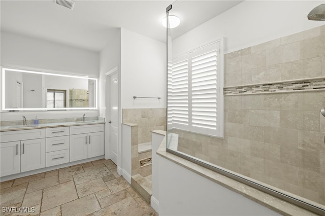 bathroom featuring vanity, a healthy amount of sunlight, and tiled shower