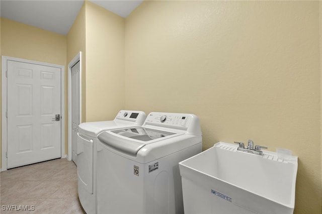 laundry area featuring light tile patterned flooring, sink, and washer and clothes dryer