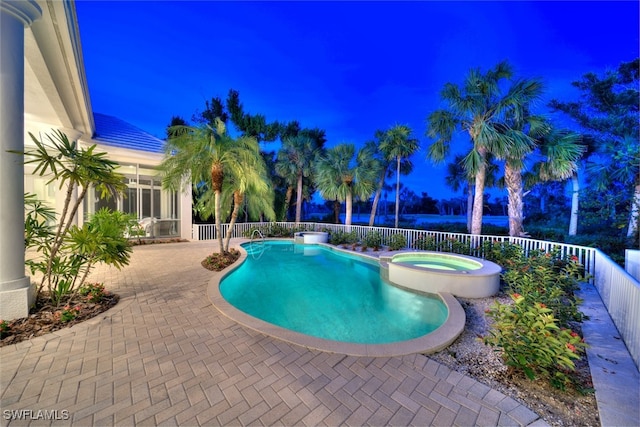 pool at dusk with a patio area and an in ground hot tub