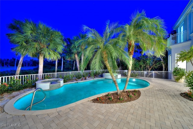 pool at twilight featuring a patio area and an in ground hot tub