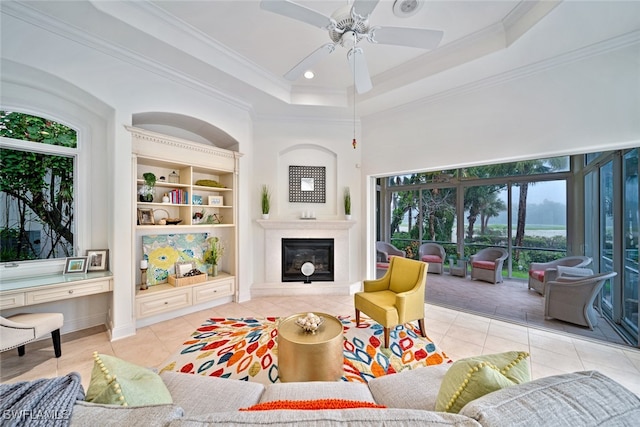 tiled living room with ornamental molding, a raised ceiling, and ceiling fan