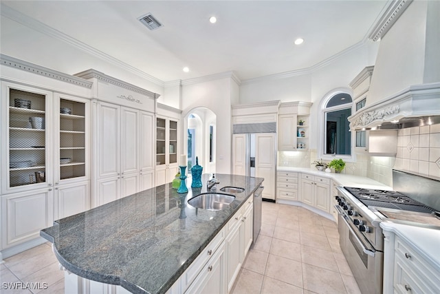 kitchen with white cabinets, backsplash, a kitchen island with sink, high quality appliances, and sink