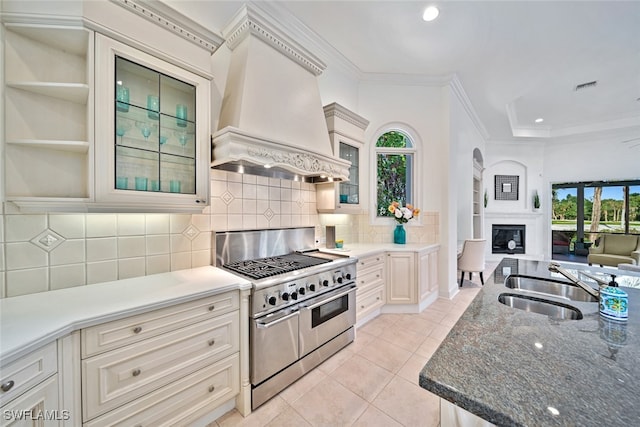 kitchen featuring range with two ovens, sink, custom exhaust hood, and plenty of natural light