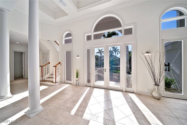 tiled foyer entrance with ornamental molding, a high ceiling, ornate columns, and french doors