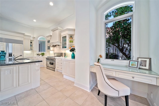 kitchen featuring custom range hood, high end range, ornamental molding, a breakfast bar, and tasteful backsplash