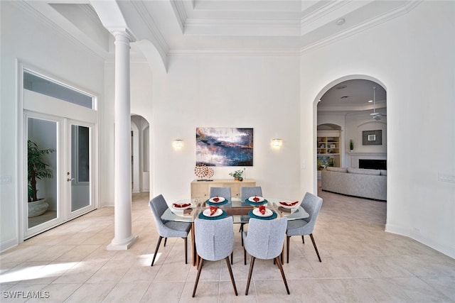 tiled dining room featuring ornate columns, ornamental molding, and a high ceiling