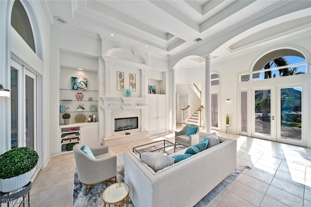 tiled living room featuring french doors, ornate columns, a premium fireplace, built in shelves, and a towering ceiling