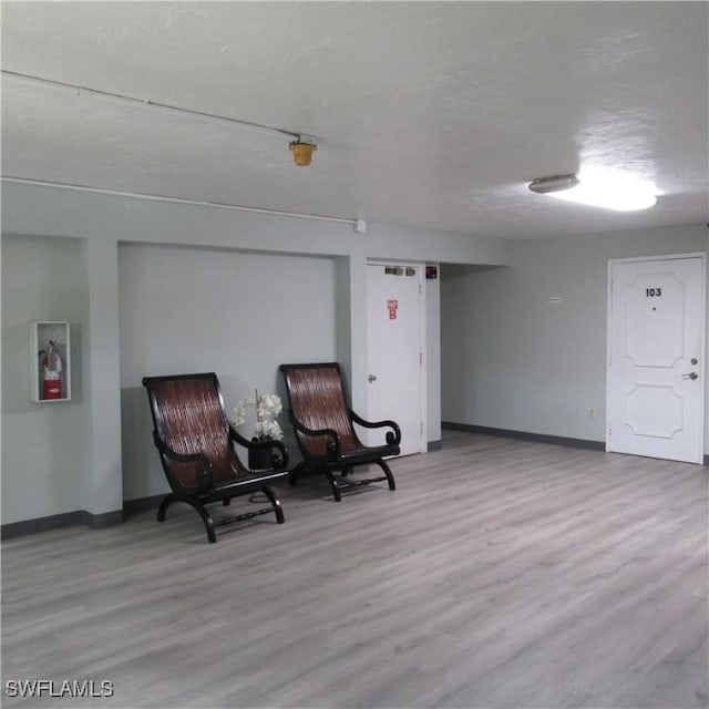 sitting room featuring a textured ceiling, baseboards, and wood finished floors