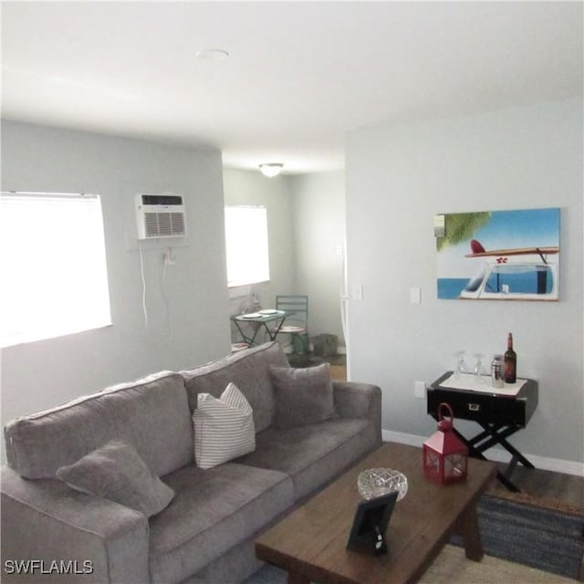 living room featuring a wall unit AC, baseboards, and wood finished floors