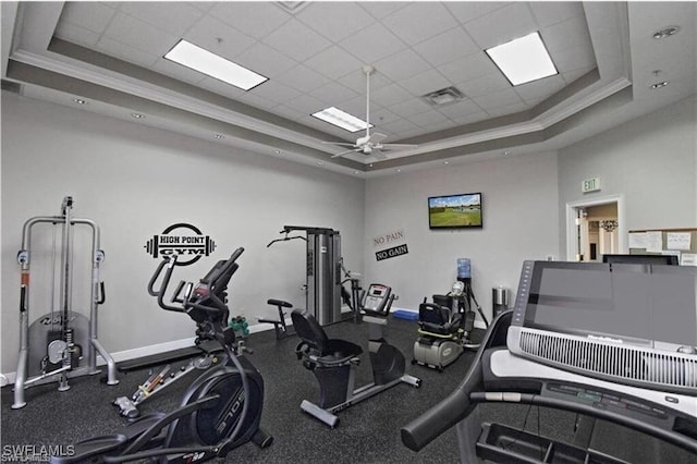 gym with crown molding, ceiling fan, and a raised ceiling