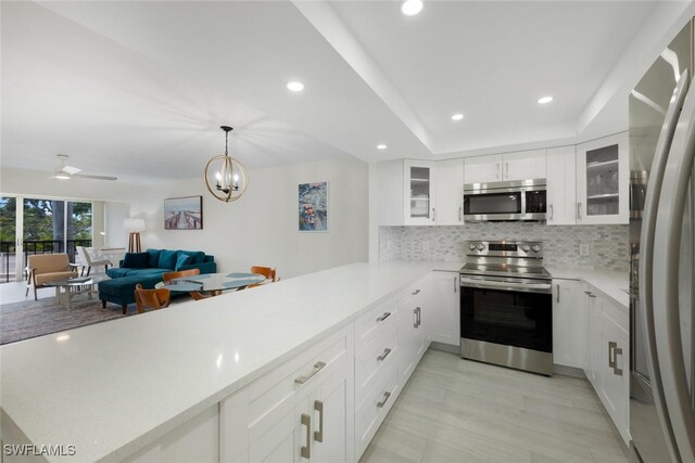 kitchen with stainless steel appliances, a tray ceiling, light countertops, and decorative backsplash