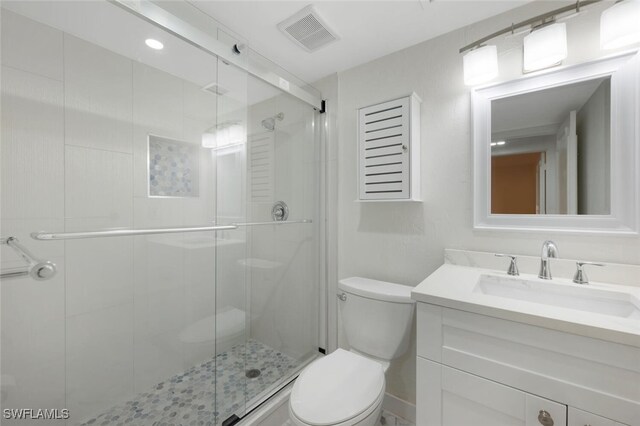 bathroom with toilet, a shower stall, visible vents, and vanity