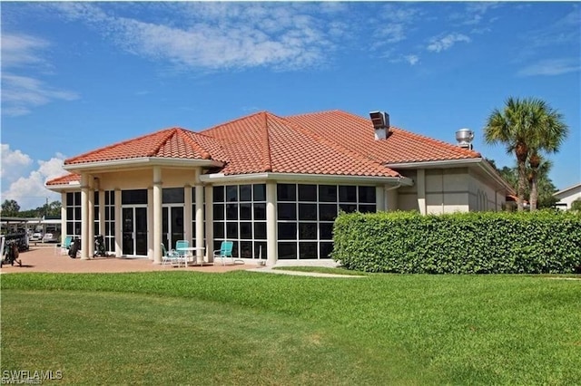 back of house featuring a tile roof, a yard, and a chimney