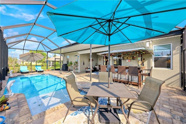 view of pool featuring a patio, glass enclosure, and an outdoor bar