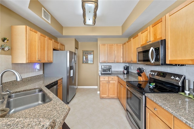 kitchen featuring appliances with stainless steel finishes, tasteful backsplash, light brown cabinetry, and sink