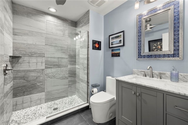 bathroom featuring tile patterned flooring, vanity, toilet, and tiled shower