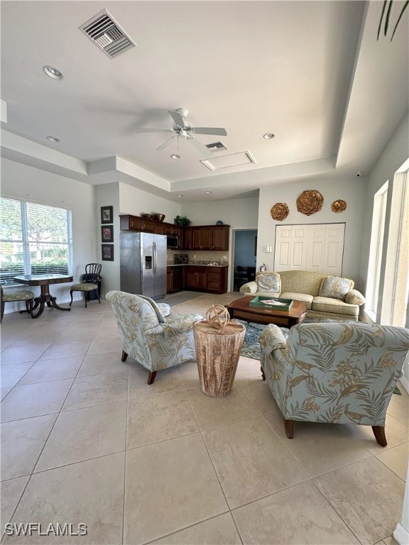 living room featuring light tile patterned floors, a tray ceiling, and ceiling fan