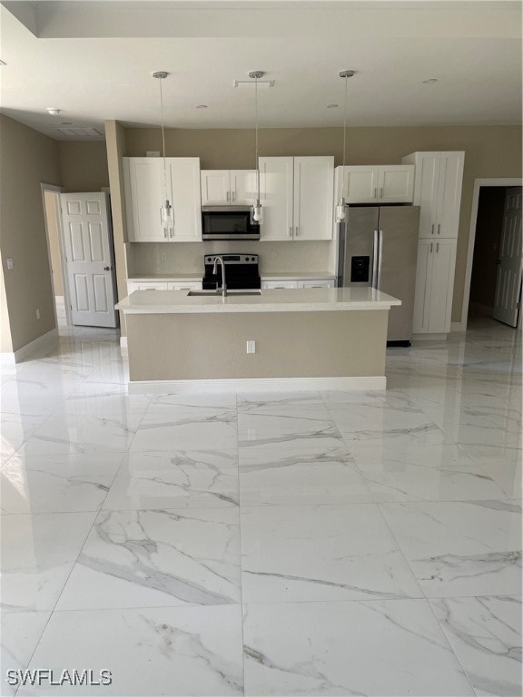 kitchen with stainless steel appliances, white cabinets, a center island with sink, and decorative light fixtures