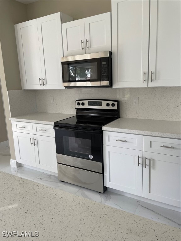 kitchen with stainless steel appliances, white cabinetry, and tasteful backsplash