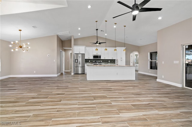 kitchen with appliances with stainless steel finishes, light stone counters, pendant lighting, and white cabinetry