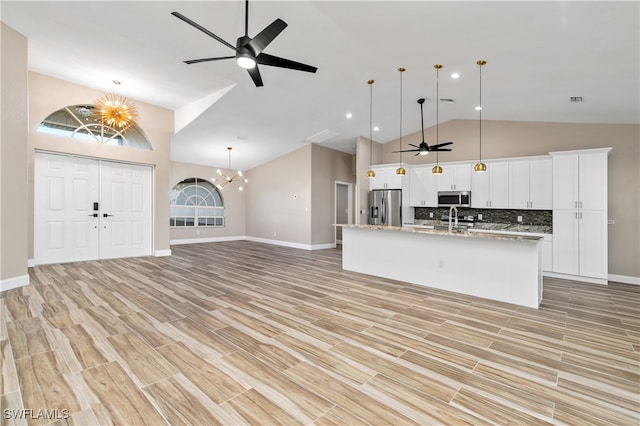 kitchen featuring pendant lighting, stainless steel appliances, white cabinetry, and an island with sink