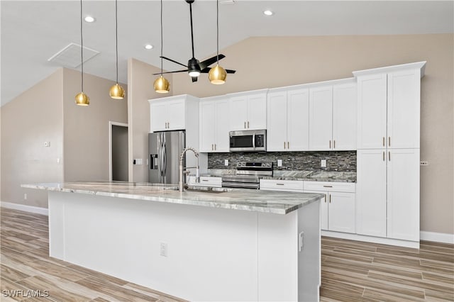 kitchen with white cabinets, a spacious island, light stone countertops, pendant lighting, and stainless steel appliances