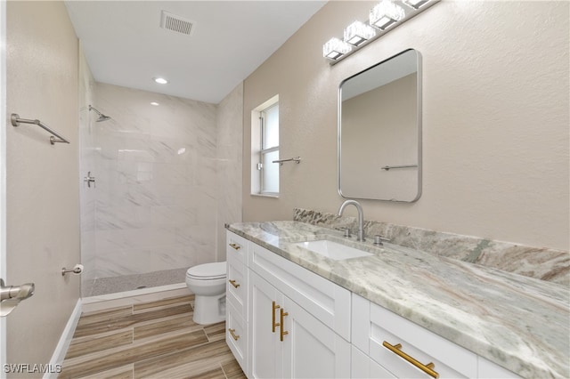 bathroom featuring vanity, toilet, and a tile shower