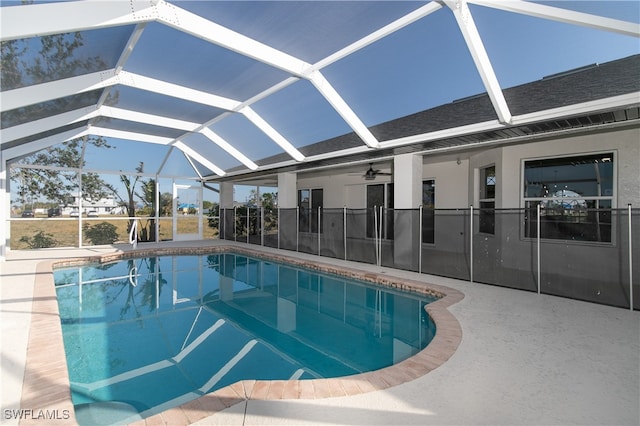 view of swimming pool featuring a patio area, glass enclosure, and ceiling fan