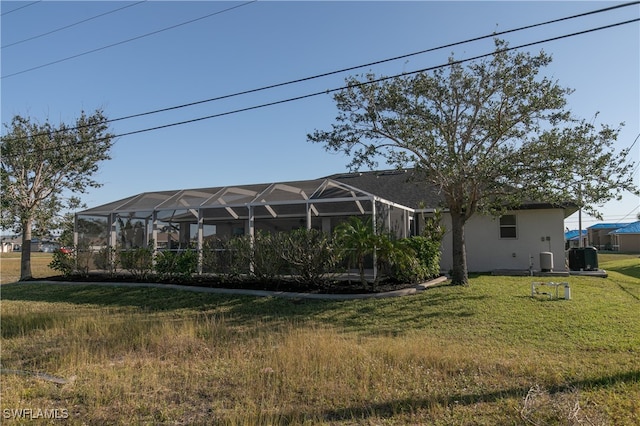 back of house featuring glass enclosure and a lawn