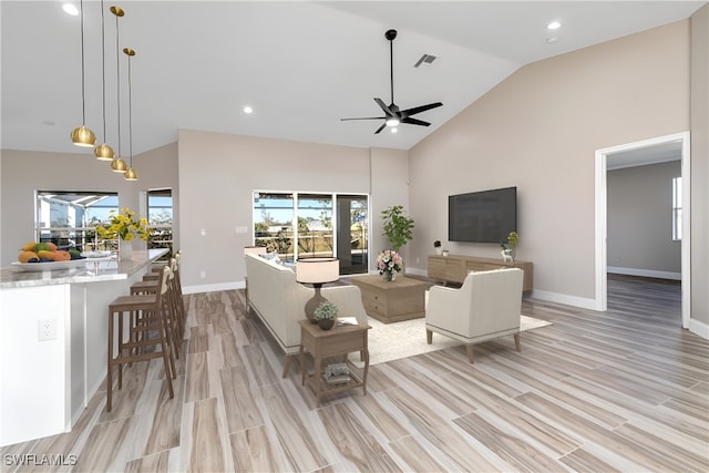 living room featuring ceiling fan, high vaulted ceiling, and light hardwood / wood-style flooring