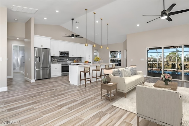 living room with light hardwood / wood-style flooring, high vaulted ceiling, and ceiling fan