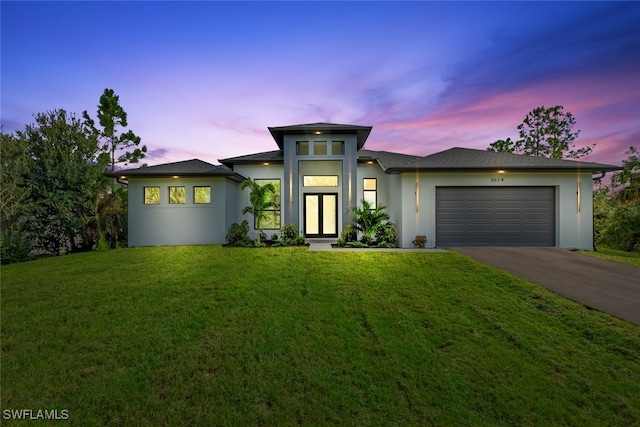 prairie-style house featuring a garage and a yard